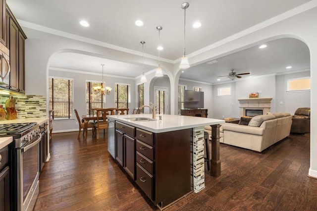 kitchen featuring light countertops, arched walkways, appliances with stainless steel finishes, and a sink