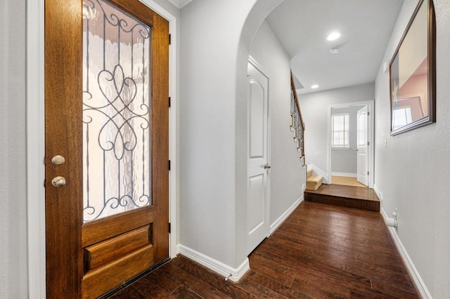 entryway with arched walkways, dark wood finished floors, stairs, recessed lighting, and baseboards