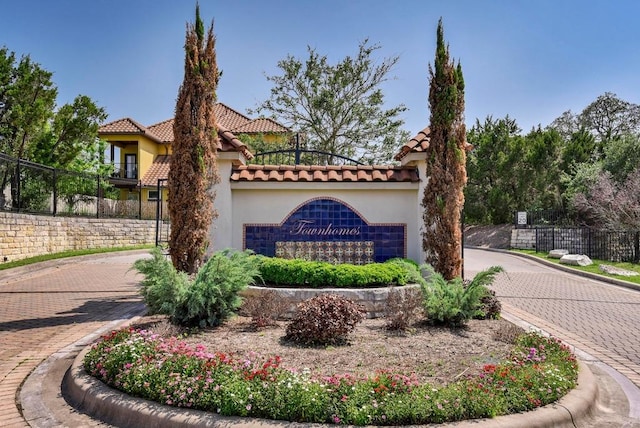 community / neighborhood sign featuring decorative driveway and fence