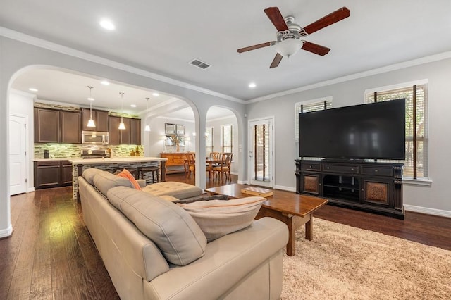 living area featuring ornamental molding, arched walkways, visible vents, and dark wood-style floors