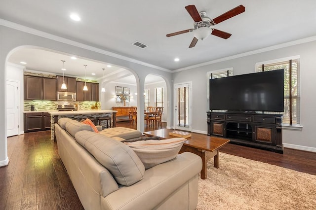 living room featuring visible vents, arched walkways, dark wood finished floors, and a ceiling fan