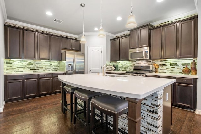 kitchen with dark brown cabinetry, dark wood-type flooring, stainless steel appliances, crown molding, and a sink