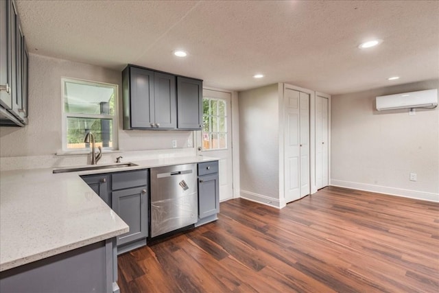 kitchen with dark wood-style floors, a textured ceiling, an AC wall unit, stainless steel dishwasher, and a sink