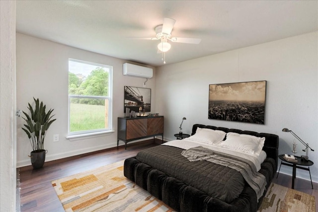bedroom featuring an AC wall unit, wood finished floors, a ceiling fan, and baseboards