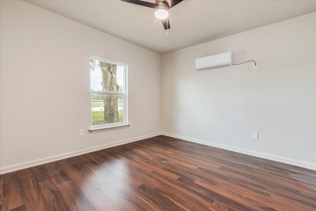 spare room featuring an AC wall unit, dark wood finished floors, baseboards, and ceiling fan