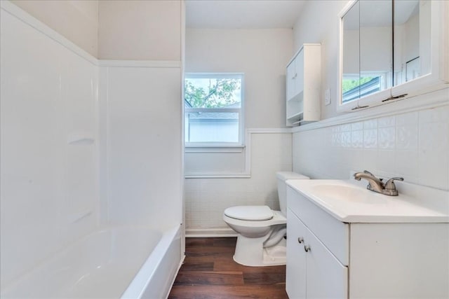 full bathroom featuring wainscoting, toilet, wood finished floors, vanity, and tile walls
