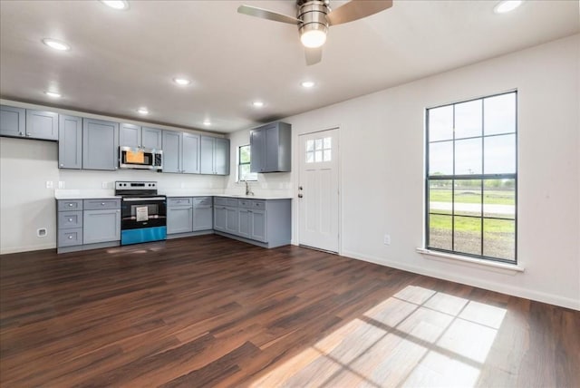 kitchen with dark wood finished floors, stainless steel appliances, recessed lighting, gray cabinets, and light countertops