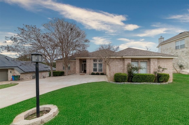 view of front of house featuring a front yard, brick siding, driveway, and roof with shingles