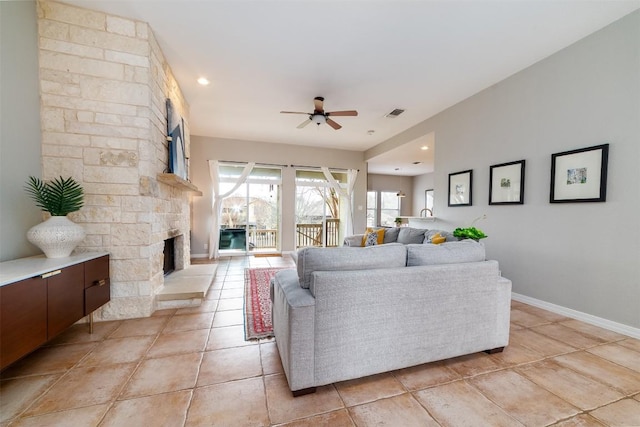 living area with light tile patterned floors, a fireplace, visible vents, baseboards, and a ceiling fan