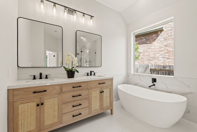 full bathroom with lofted ceiling, a freestanding tub, a sink, a marble finish shower, and double vanity