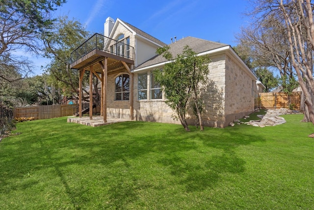 back of property featuring stone siding, a fenced backyard, a chimney, and a yard