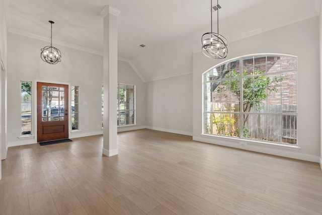 entrance foyer featuring a chandelier, baseboards, wood finished floors, and crown molding