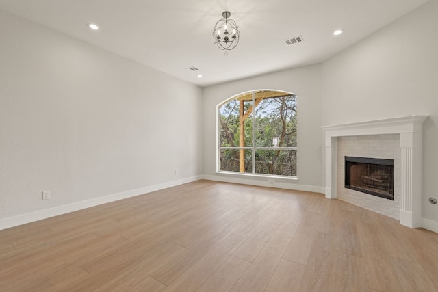 unfurnished living room with light wood finished floors, baseboards, visible vents, a fireplace, and recessed lighting