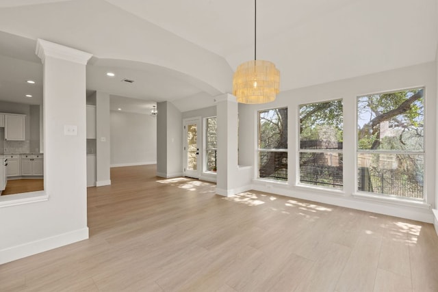 interior space featuring arched walkways, light wood finished floors, visible vents, and baseboards