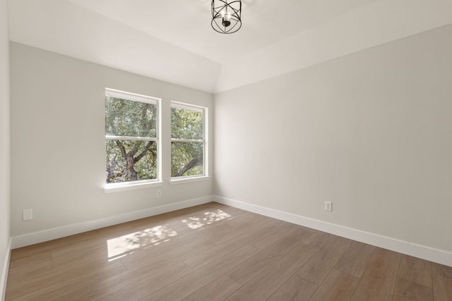 empty room with vaulted ceiling, wood finished floors, and baseboards