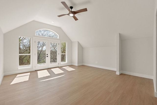 additional living space featuring french doors, lofted ceiling, light wood-style flooring, a ceiling fan, and baseboards