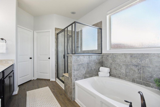 full bathroom with a stall shower, a garden tub, vanity, and wood finished floors