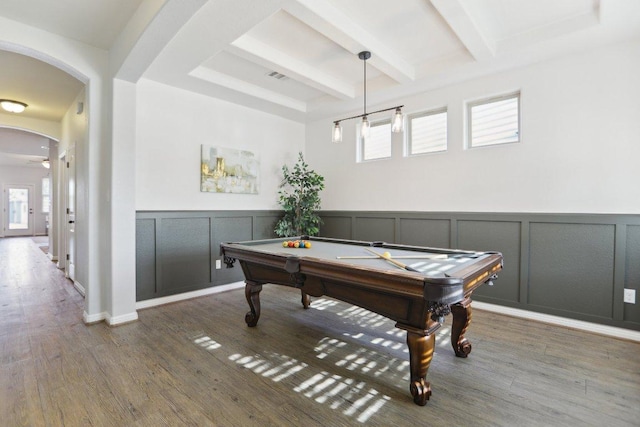 rec room with arched walkways, a decorative wall, wood finished floors, visible vents, and beam ceiling