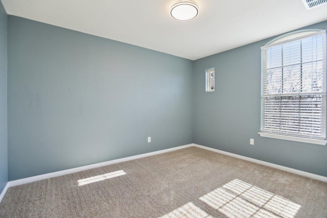 unfurnished room with carpet floors, visible vents, and baseboards