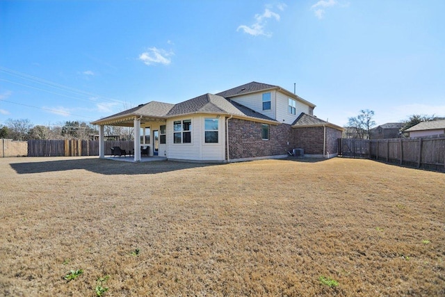 back of house featuring a yard, a fenced backyard, a patio, and brick siding