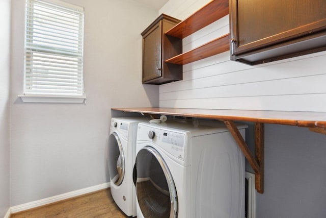 washroom featuring cabinet space, light wood-style flooring, baseboards, and independent washer and dryer