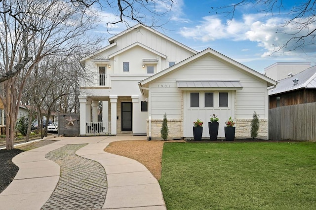 view of front of house featuring stone siding, a front lawn, board and batten siding, and a balcony