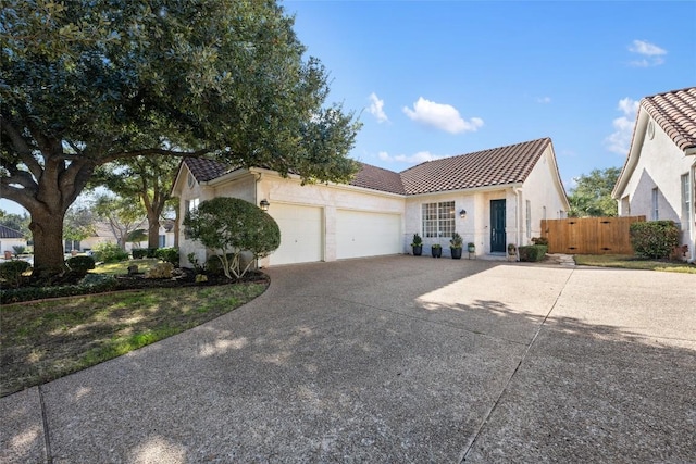 ranch-style home with stucco siding, fence, a garage, driveway, and a tiled roof