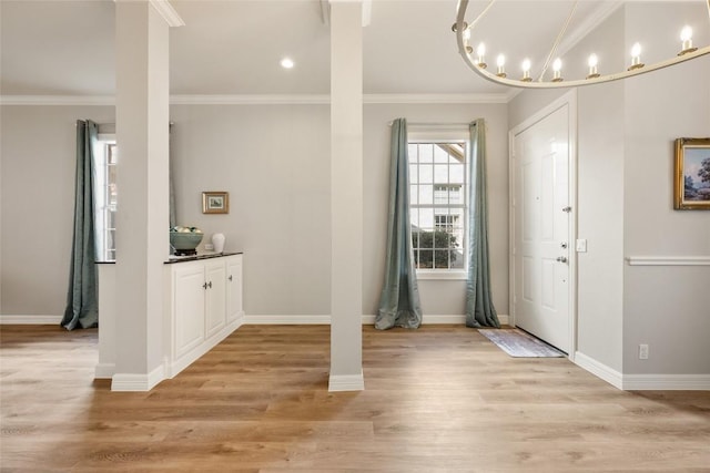 foyer entrance with light wood-style floors, ornamental molding, and baseboards