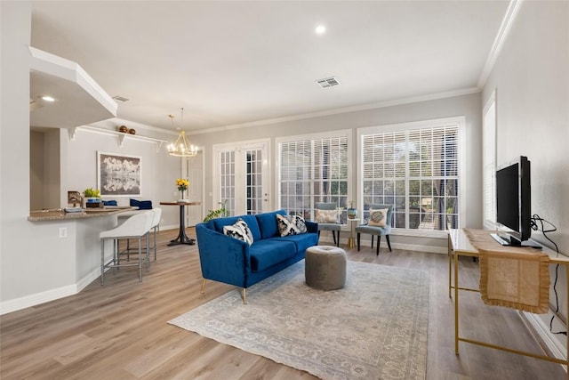 living room with light wood-style flooring, visible vents, ornamental molding, and baseboards