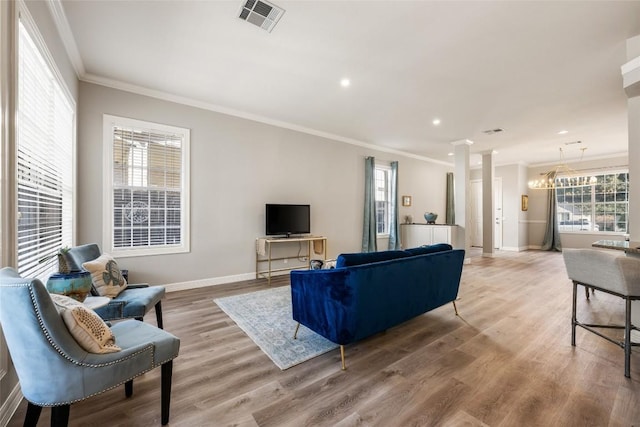 living room with visible vents, baseboards, ornamental molding, light wood-type flooring, and decorative columns