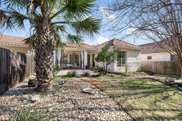 view of front of house featuring a ceiling fan, a patio, a tile roof, fence, and stucco siding