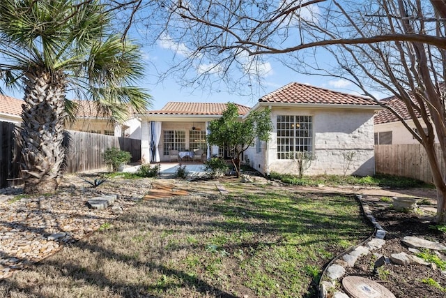 view of front of home with a front lawn, a fenced backyard, a tile roof, and stucco siding