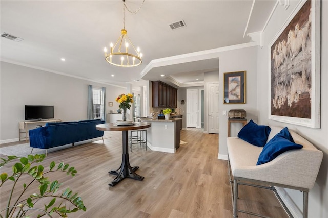 living room with light wood-type flooring, visible vents, and ornamental molding