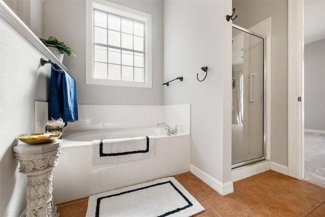 full bath featuring tile patterned flooring, a shower stall, baseboards, and a bath