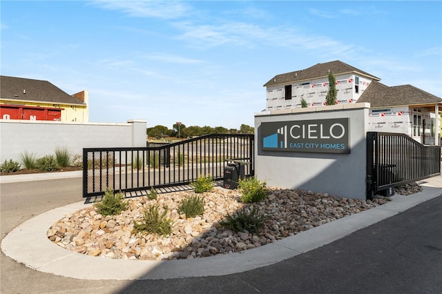 community sign featuring a gate and fence