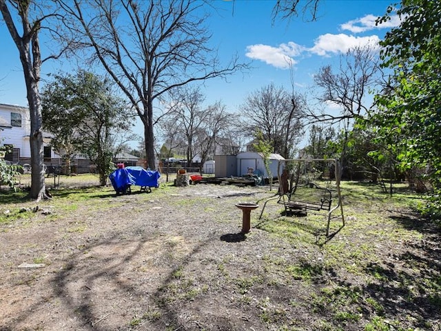 view of yard featuring a storage unit, an outdoor structure, and fence