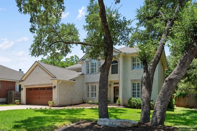 view of front of home featuring an attached garage, brick siding, a front yard, and fence