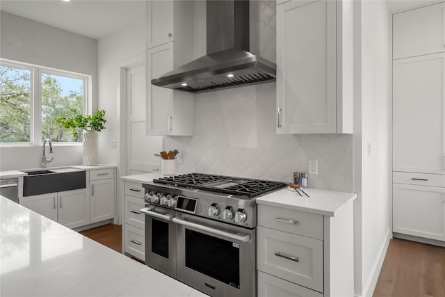 12120 Fitzhugh Pl, Dripping Springs, TX 78620 - kitchen with stainless steel gas range, wall chimney exhaust hood, a sink, backsplash, and wood finished floors