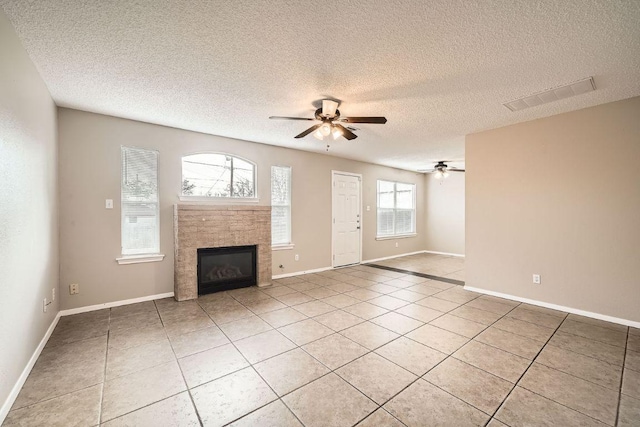 unfurnished living room with light tile patterned floors, visible vents, baseboards, a ceiling fan, and a tiled fireplace