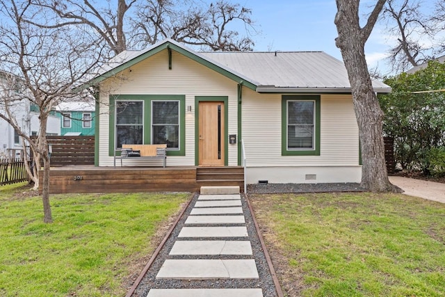 view of front of house with a front yard, crawl space, fence, and metal roof