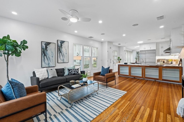 living area with light wood finished floors, a ceiling fan, visible vents, and recessed lighting