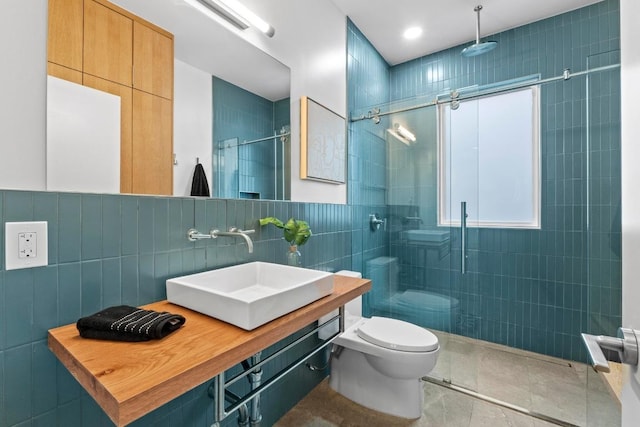 full bathroom featuring toilet, vanity, tile walls, tile patterned floors, and a stall shower