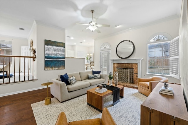 living area featuring baseboards, visible vents, wood finished floors, crown molding, and a fireplace