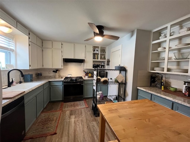 kitchen featuring under cabinet range hood, open shelves, a sink, black appliances, and dark wood finished floors