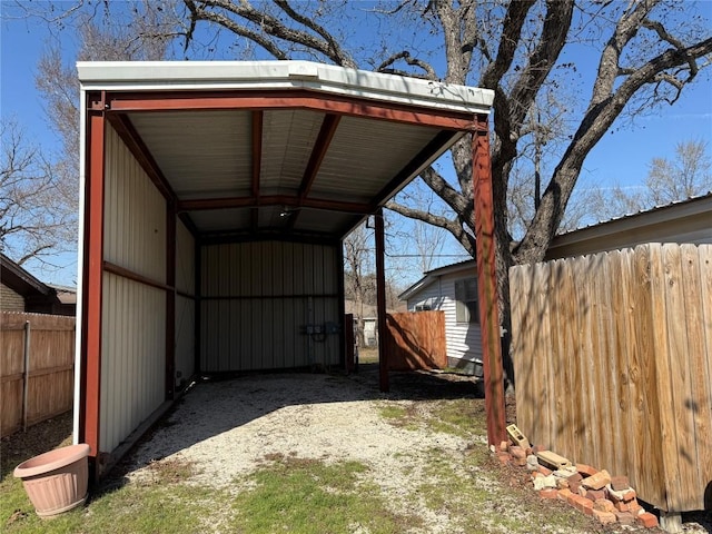 exterior space featuring driveway, fence, and a carport