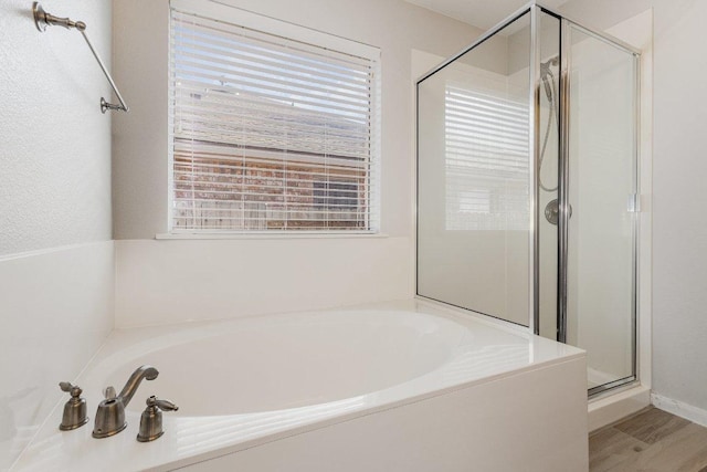 full bath featuring a shower stall, a bath, and wood finished floors