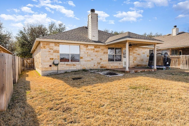 back of property with a patio area, stone siding, a fenced backyard, and a lawn