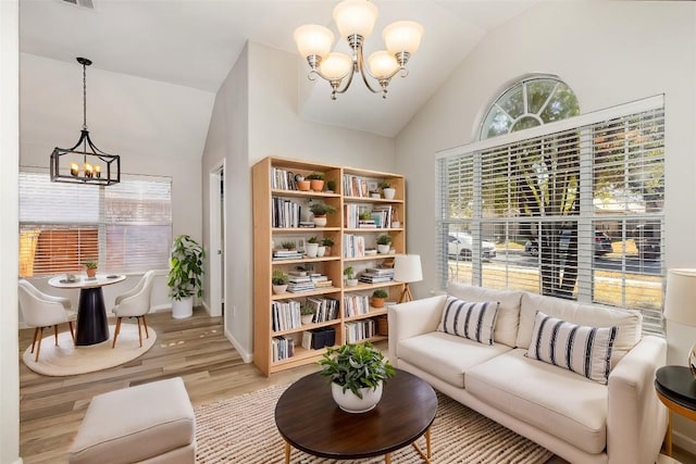 living area with vaulted ceiling, baseboards, light wood-style flooring, and an inviting chandelier