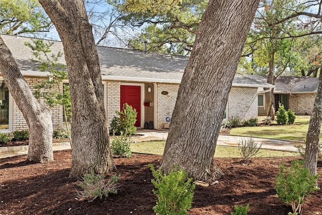 view of front facade with a shingled roof and brick siding