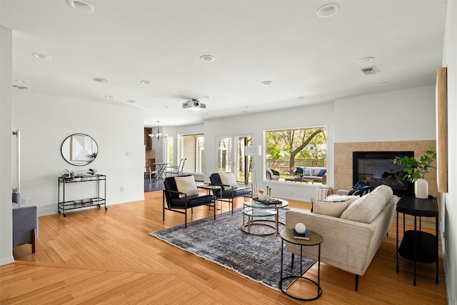 living area featuring recessed lighting, a notable chandelier, a fireplace, visible vents, and light wood finished floors